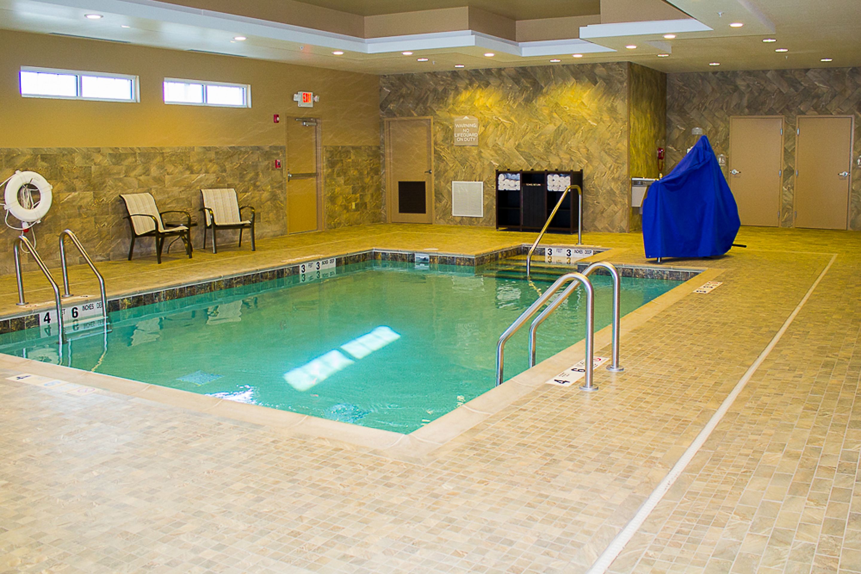 Une piscine intérieure à l’eau claire, dotée d’un poste de surveillance pour le sauveteur et de chaises abritées.