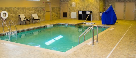 An indoor swimming pool with clear water, a lifeguard chair, and a covered chair.