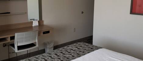 Ein Hotelzimmer mit einem Bett, einem Schreibtisch, einem Sessel, einem Fernseher und einem Rauchmelder.