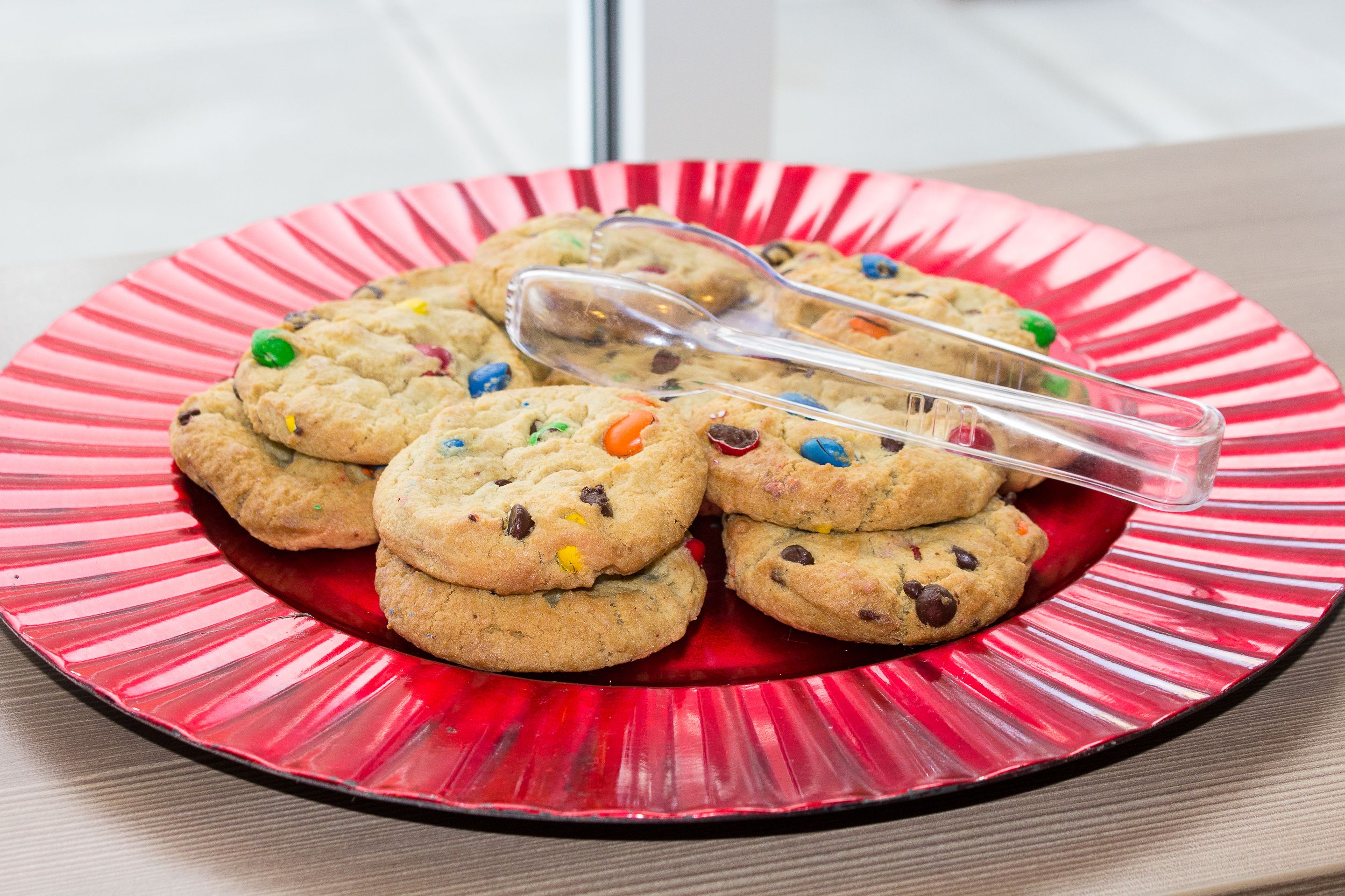 A plate of cookies with colorful candies on a red plate.