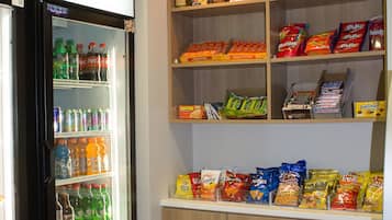 A vending machine stocked with various snacks and a refrigerator with beverages.