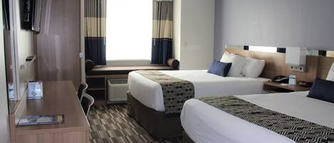 Une chambre d’hôtel avec deux lits, un bureau, une télévision et une fenêtre avec des rideaux.