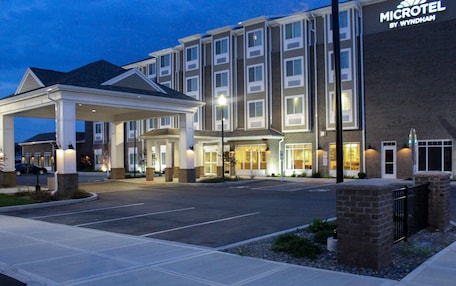 A Microtel by Wyndham hotel with a covered entrance, a parking lot, and a brick facade.