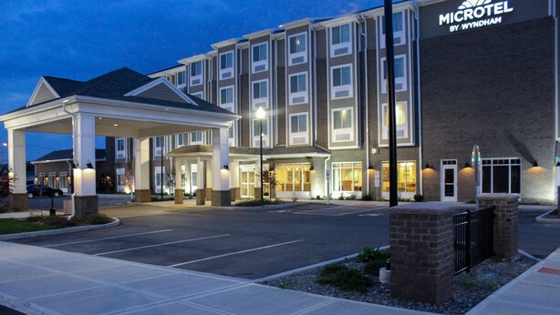 A Microtel by Wyndham hotel with a covered entrance, a parking lot, and a brick facade. - Microtel by Wyndham Penn Yan Finger Lakes Region (Penn Yan)