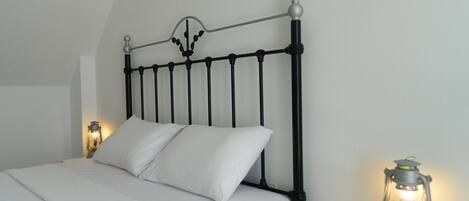 A bed with a black metal headboard, white bedding, and two bedside tables with lantern-style lamps.