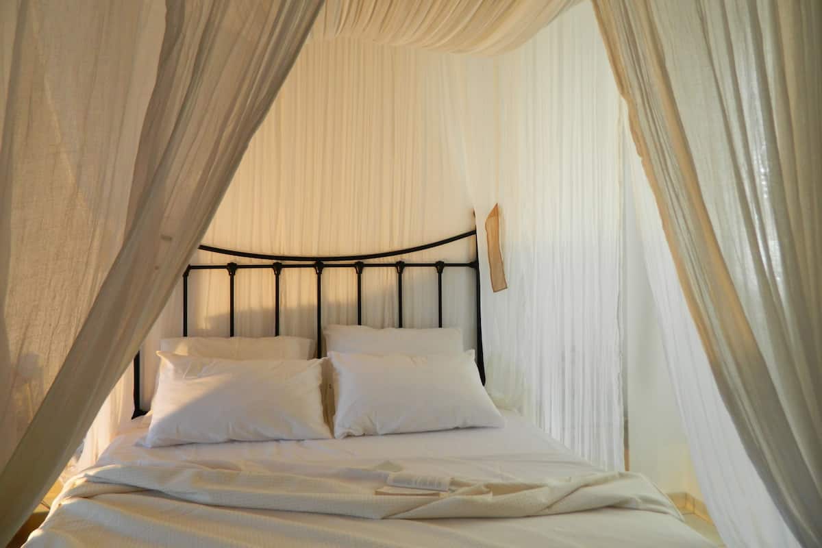 A bed with a canopy, white bedding, and a metal headboard.
