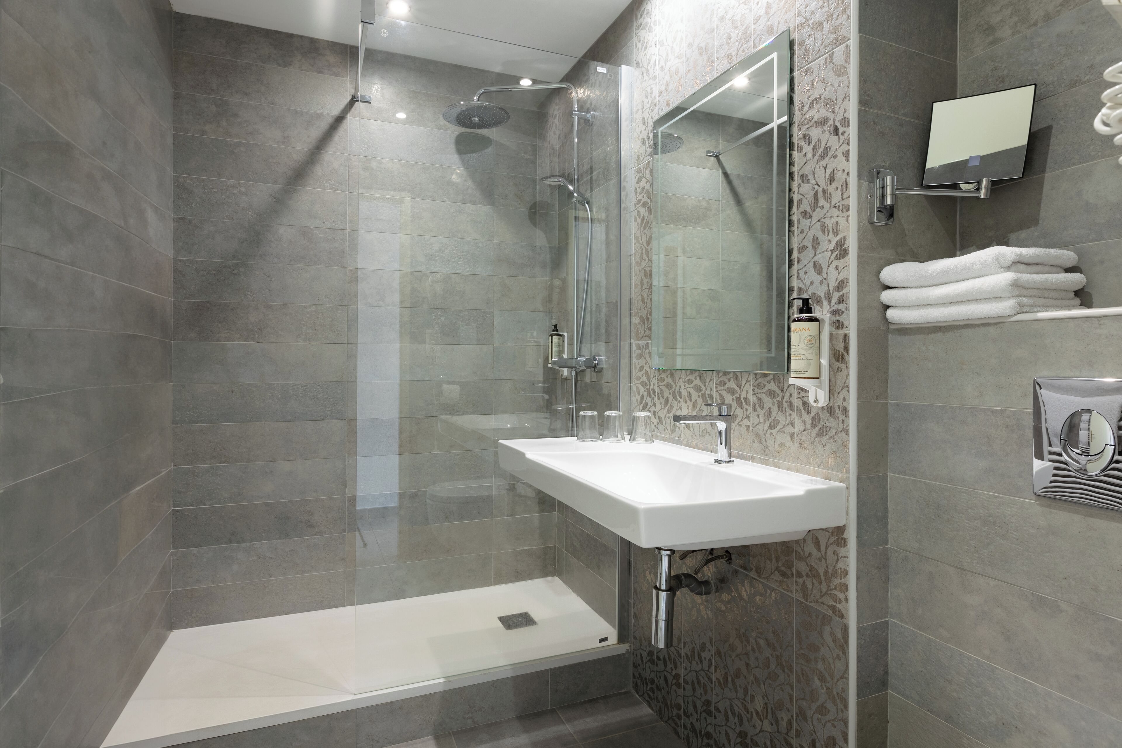 A modern bathroom with a glass-enclosed shower, a white sink, and a mirror.