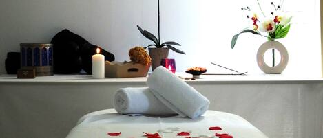 Ein Massagestuhl mit Rosenblättern, einer Kerze und einer Topforchidee.