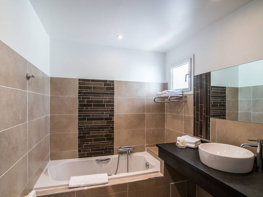 Un baño moderno con bañera, lavamanos y un espejo grande.