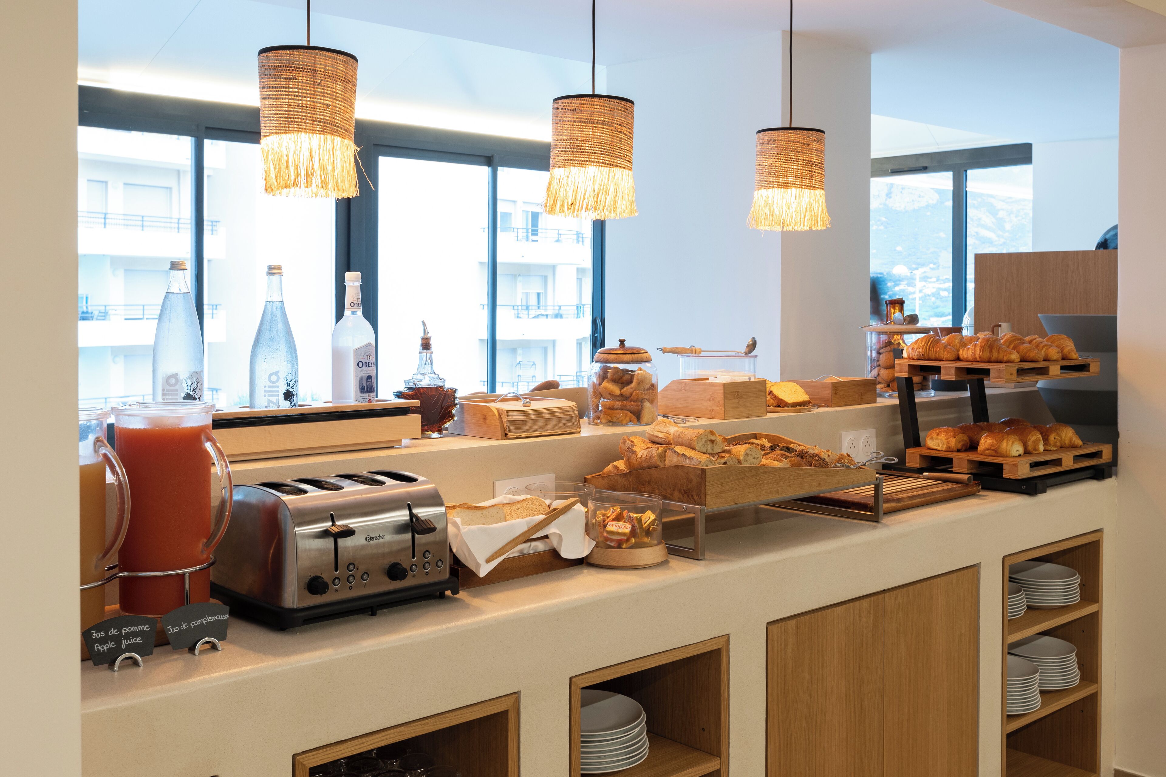 A breakfast bar with various food items, a toaster, and a juice dispenser.