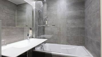 Un baño moderno con ducha envuelta en vidrio, un lavabo blanco y una bañera.