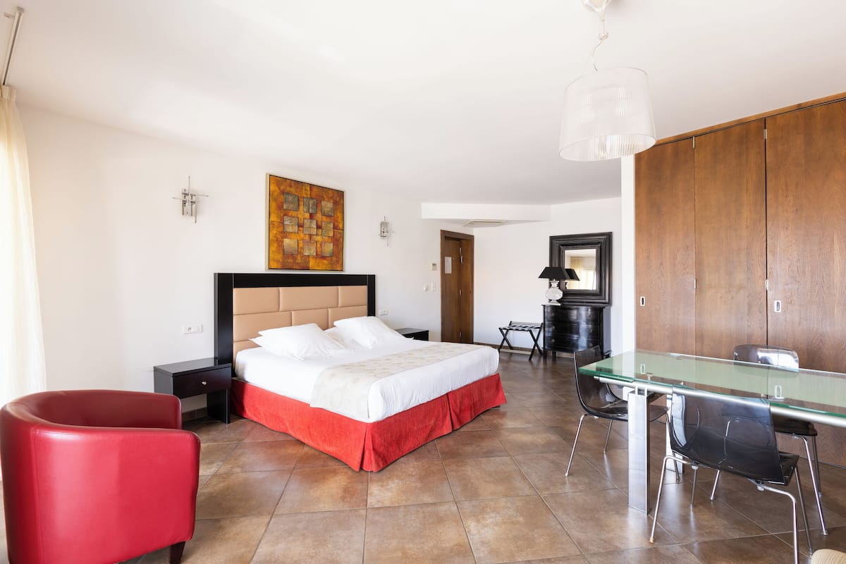 Una habitación de hotel con una cama, un escritorio, una silla y un sillón rojo.