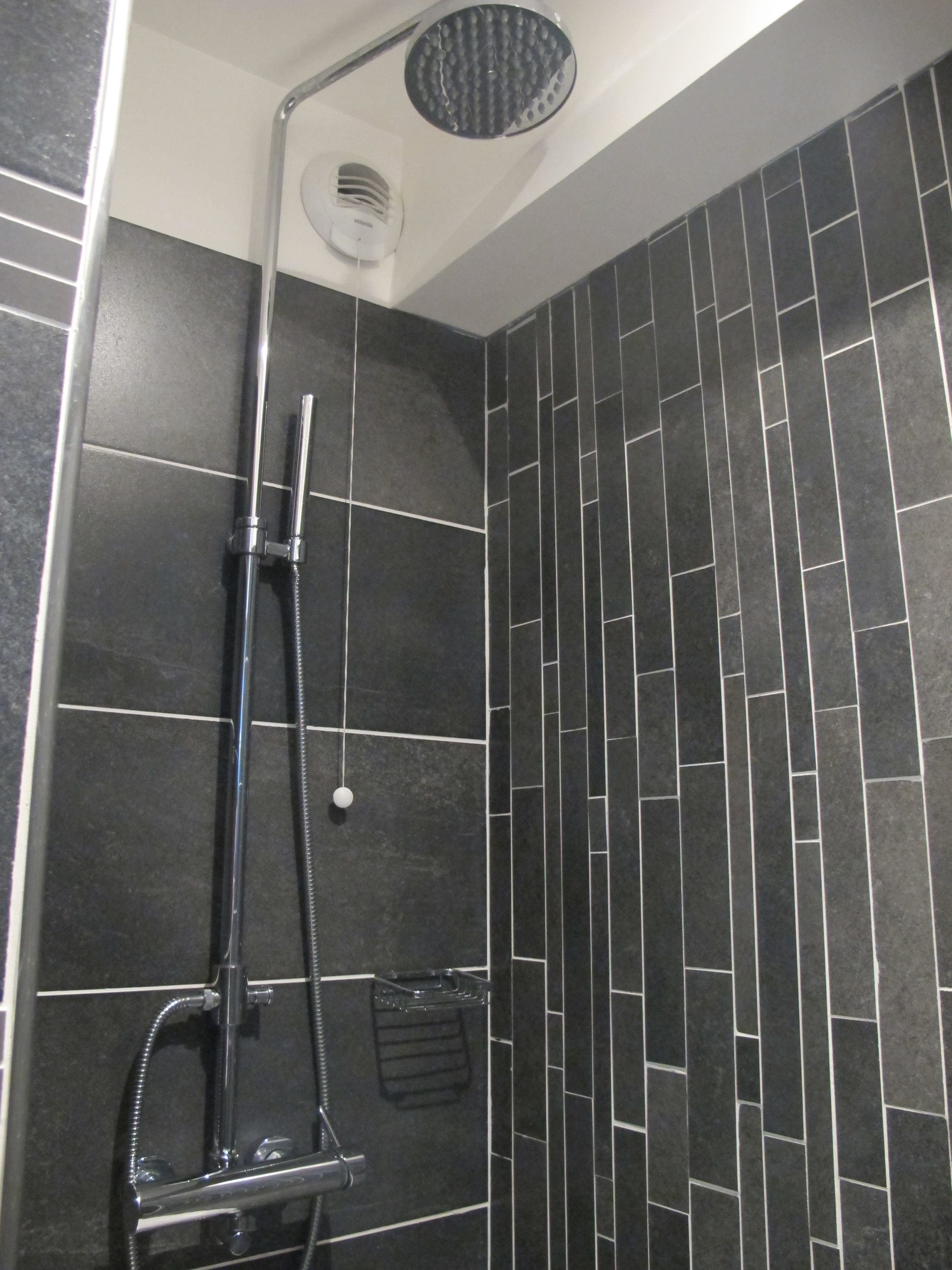 Une douche équipée d’un pommeau de douche à main et d’un pommeau de douche à pluie fixé au mur.