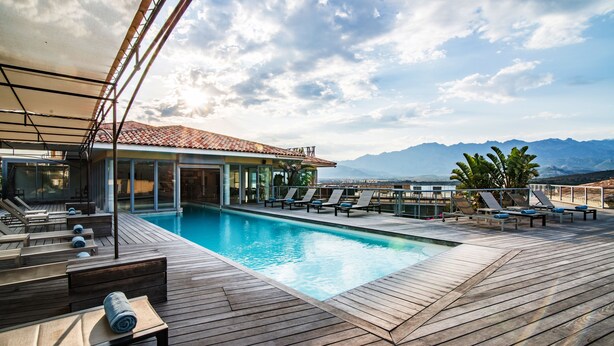 Eine Holzterrasse mit Pool, Liegestühlen und einem Gebäude mit einem Ziegeldach.
