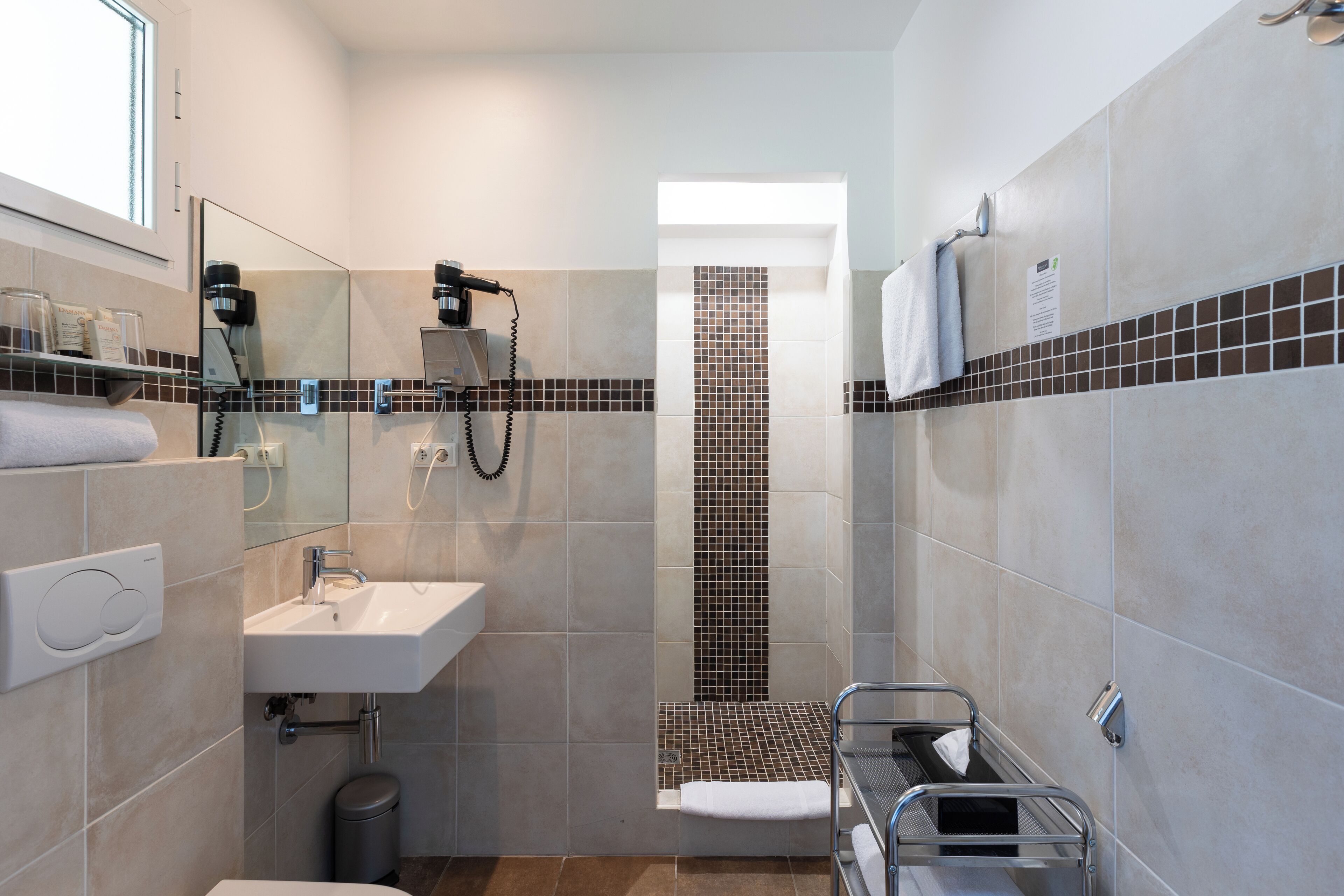 A modern bathroom with a shower, sink, and towel rack.