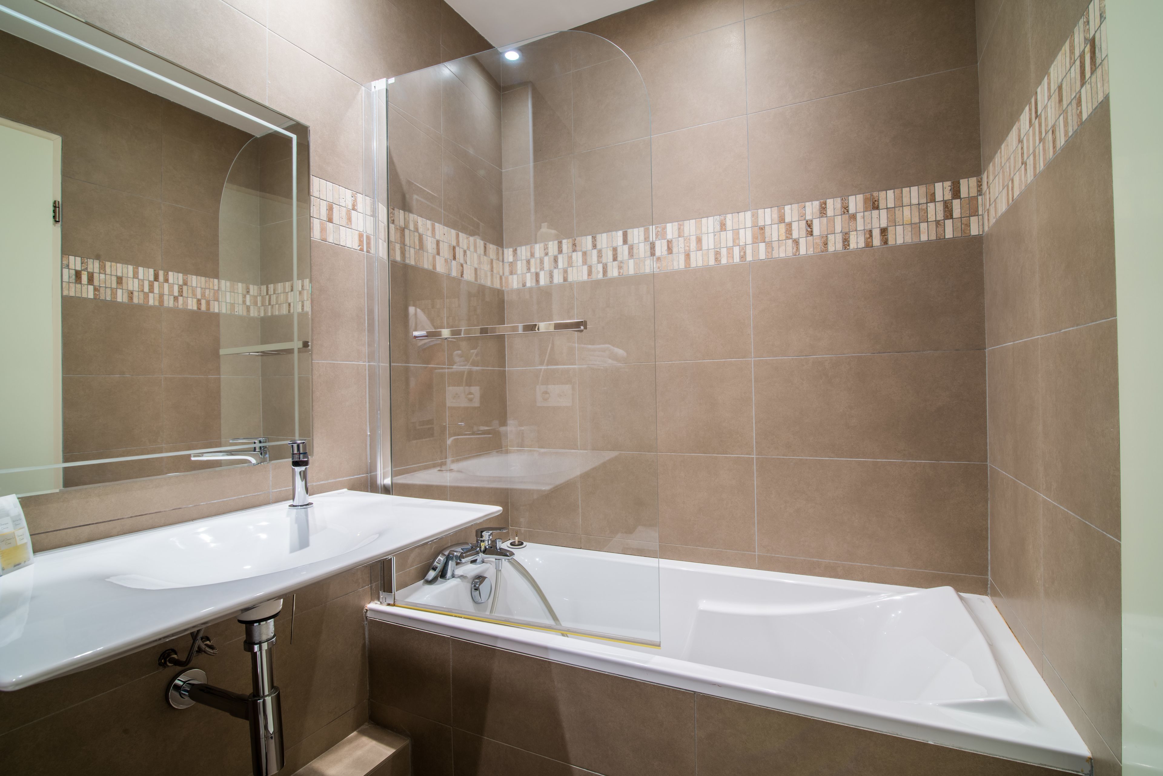 A modern bathroom with a glass-enclosed shower, a white sink, and a bathtub.