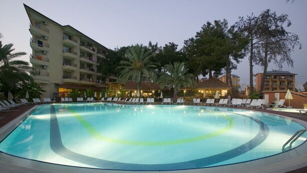 A swimming pool with lounge chairs and palm trees. - Palm Dor Hotel (Manavgat)