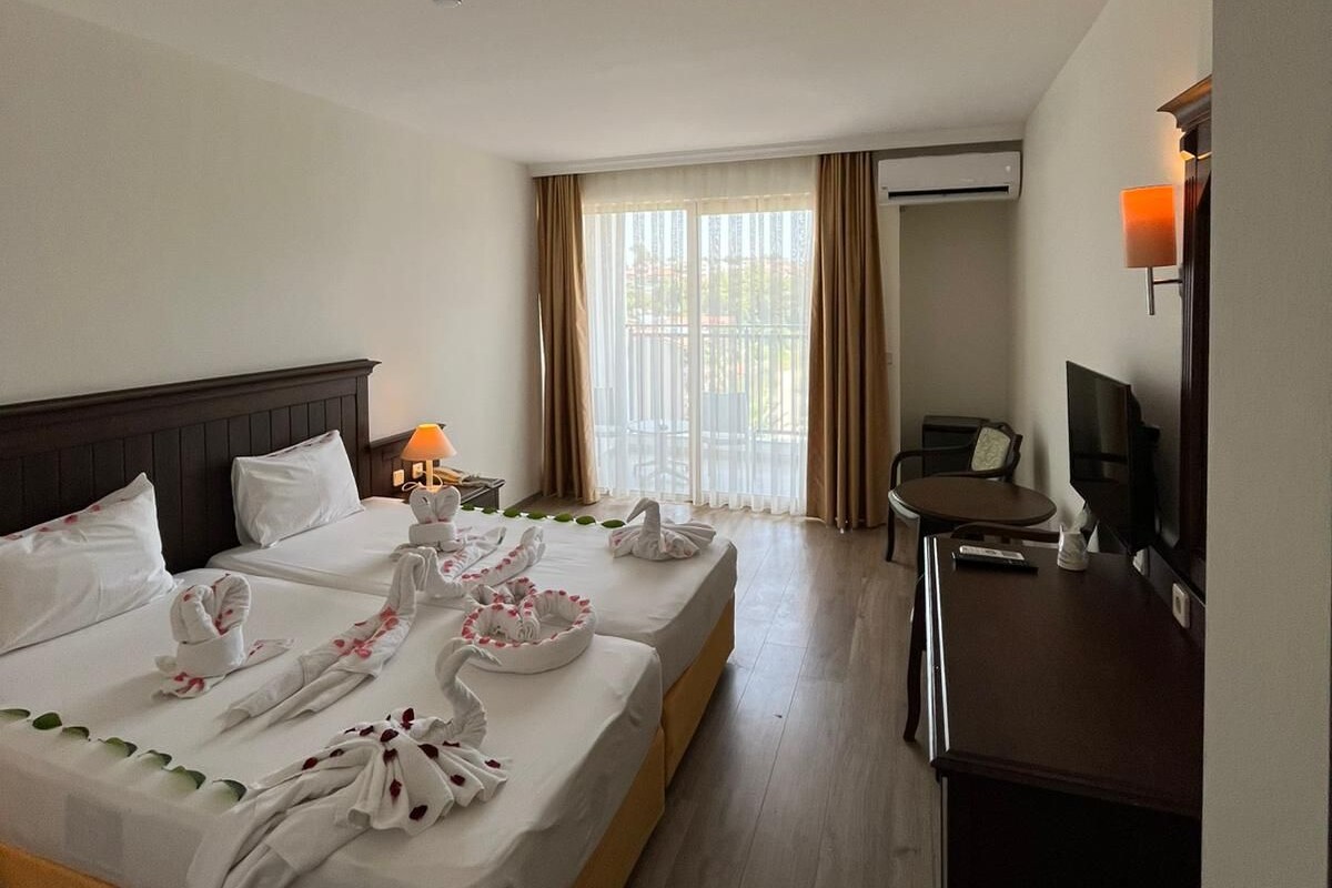 Habitación de hotel con dos camas, un escritorio, una silla, un equipo de aire acondicionado y un televisor.