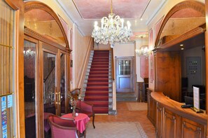 A grand staircase leading to an upper floor, a reception desk, and a chandelier. - Renesance Krasna Kralovna (Karlovy Vary)