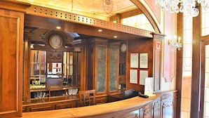A reception area with a wooden counter, a clock, and a chandelier. - Renesance Krasna Kralovna (Karlovy Vary)