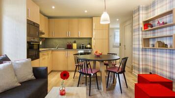 Une cuisine moderne avec des meubles en bois, une table à manger avec des chaises et un mur d’accent rouge.