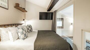 Une chambre d’hôtel avec un lit, des oreillers, un téléviseur fixé au mur et une fenêtre avec des rideaux.