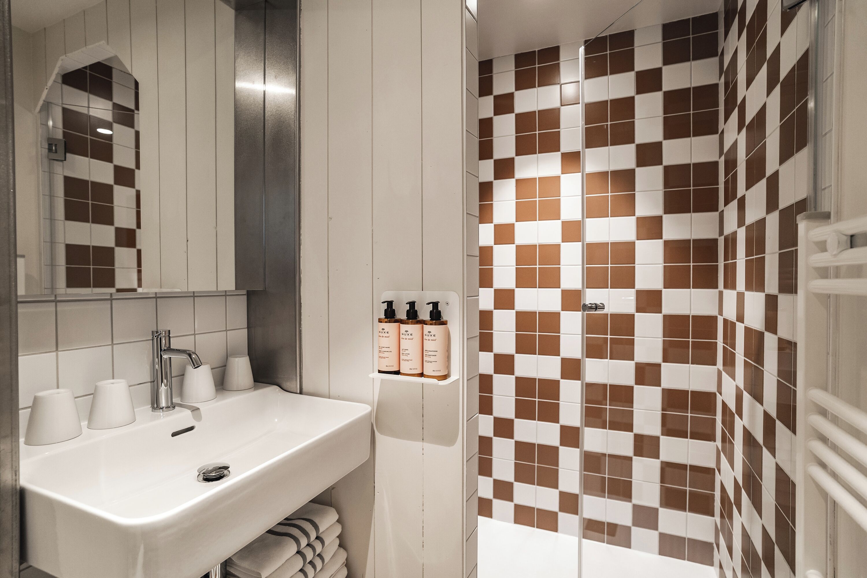 A bathroom with a white sink, mirror, and checkered tile walls.