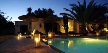 Una piscina al aire libre, sombrillas, sillones reclinables de piscina