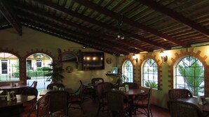 Un restaurante con techos altos, ventanas arqueadas y mobiliario de mimbre.