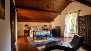 Une chambre à coucher avec un lit, une chaise, une table et une fenêtre avec des rideaux.