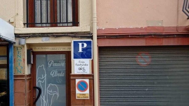 En bygning med lukket markise, et parkeringsskilt og et skilt med 'Pension Alveda'.