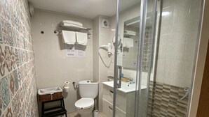 Et badeværelse med bruser, toilet og håndvask.