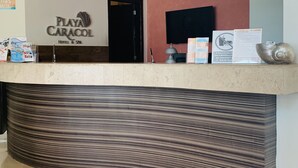 Una recepción de hotel con un cartel que dice "Playa Caracol Hotel & Spa".