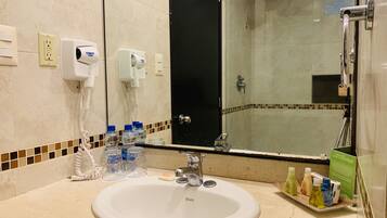 Un baño de hotel con lavabo, espejo y ducha.