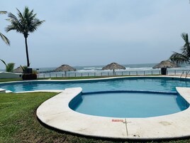 Una piscina al aire libre, sombrillas, sillones reclinables de piscina