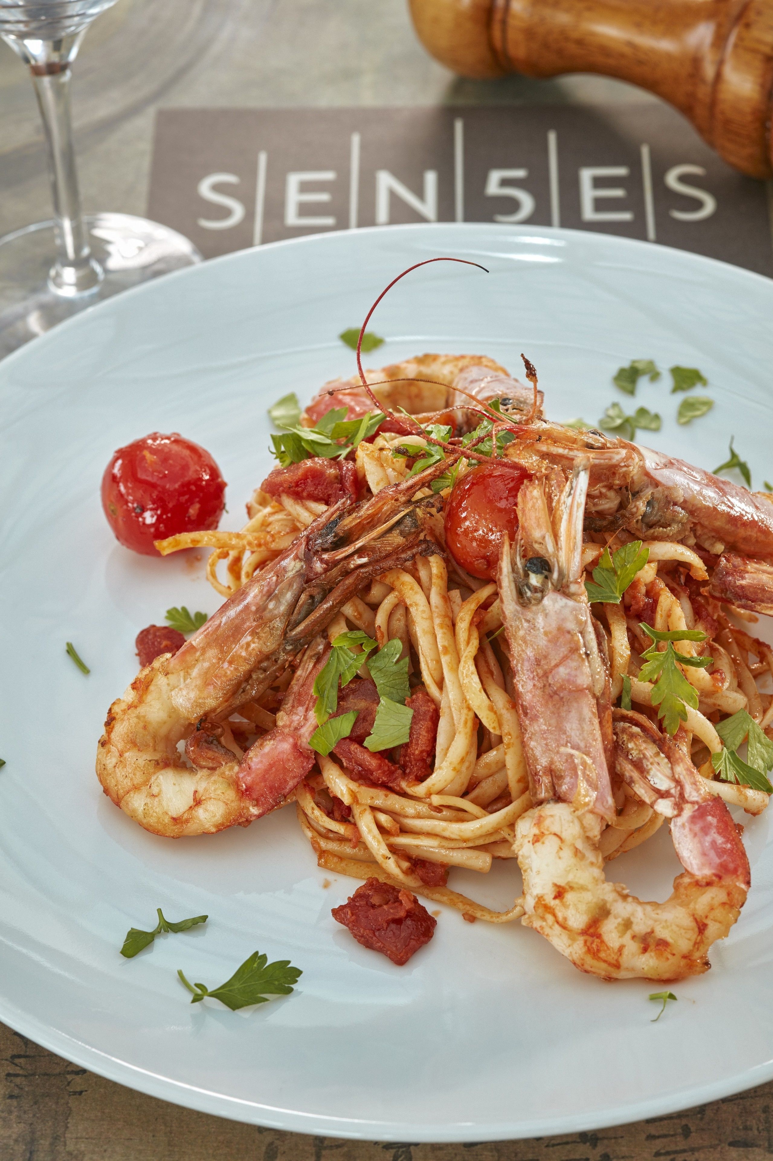 Un plato de pasta con camarones y tomates cherry.