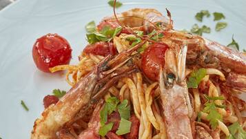 Un plato de pasta con camarones y tomates cherry.