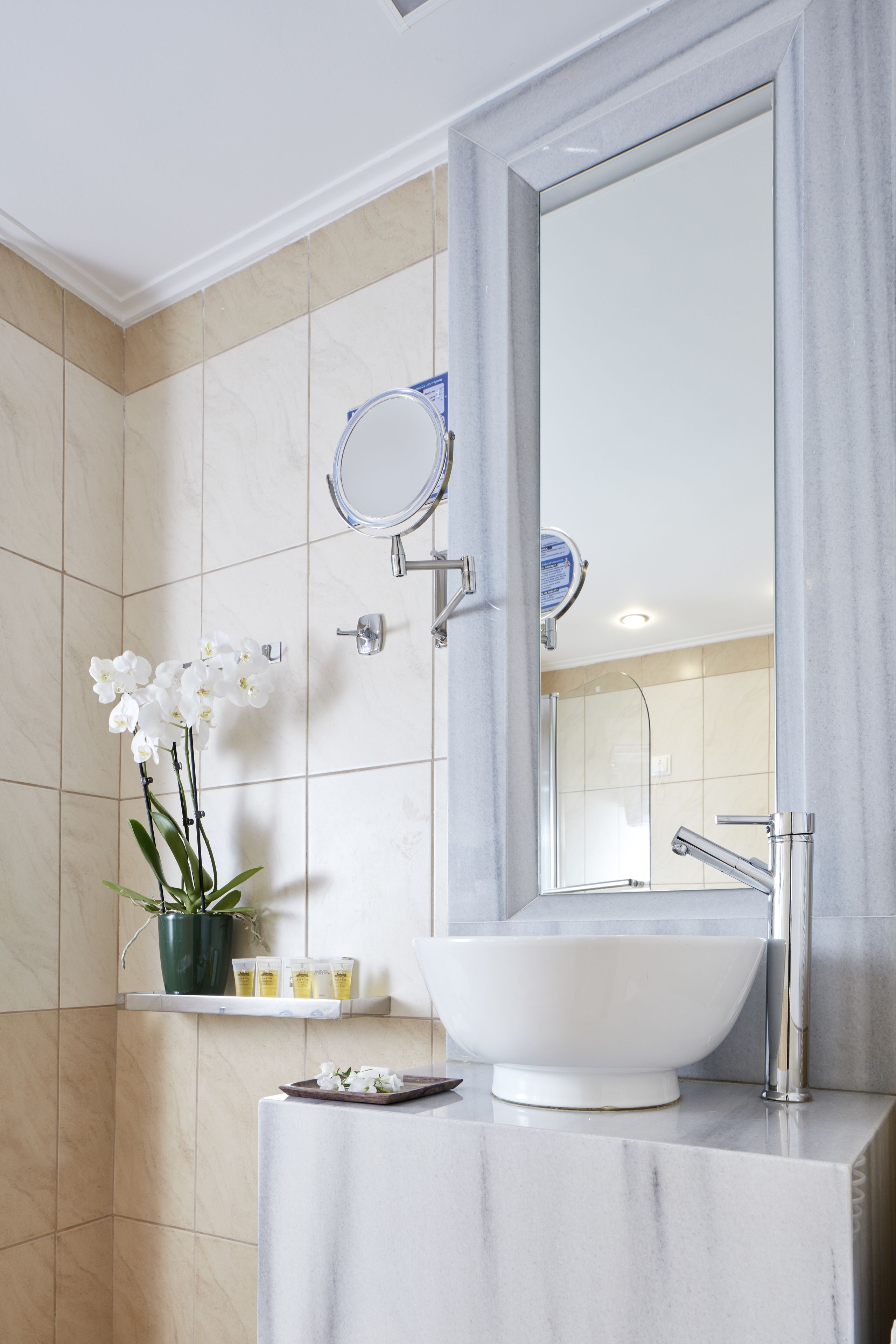 Un bagno con un lavandino bianco, uno specchio e una doccia.