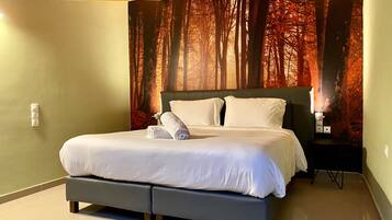 Una habitación de hotel moderna con una cama grande, una mesita de noche y un mural en la pared con un bosque.