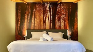 Un grand lit avec une tête de lit, deux tables de chevet et une serviette enroulée posée sur le lit.