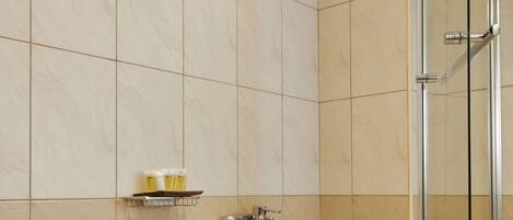 A modern bathroom with a glass-enclosed shower, a white bathtub, and a shelf with toiletries.