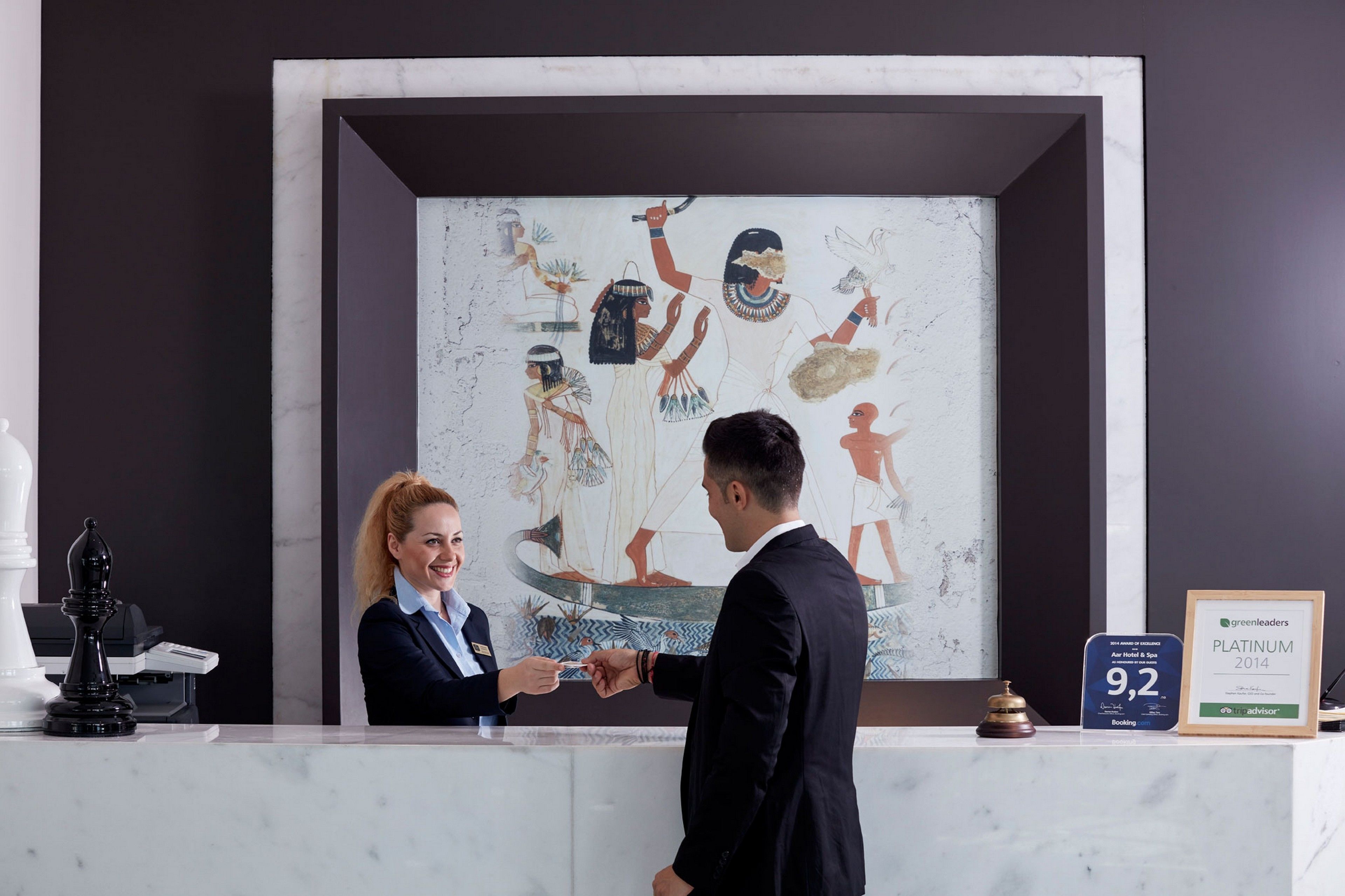 A reception desk with a framed ancient Egyptian artwork, a Platinum award plaque, and a 9.2 rating sign.