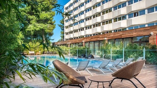 A hotel pool area with lounge chairs and a wooden deck. - C Suites (Nîmes)