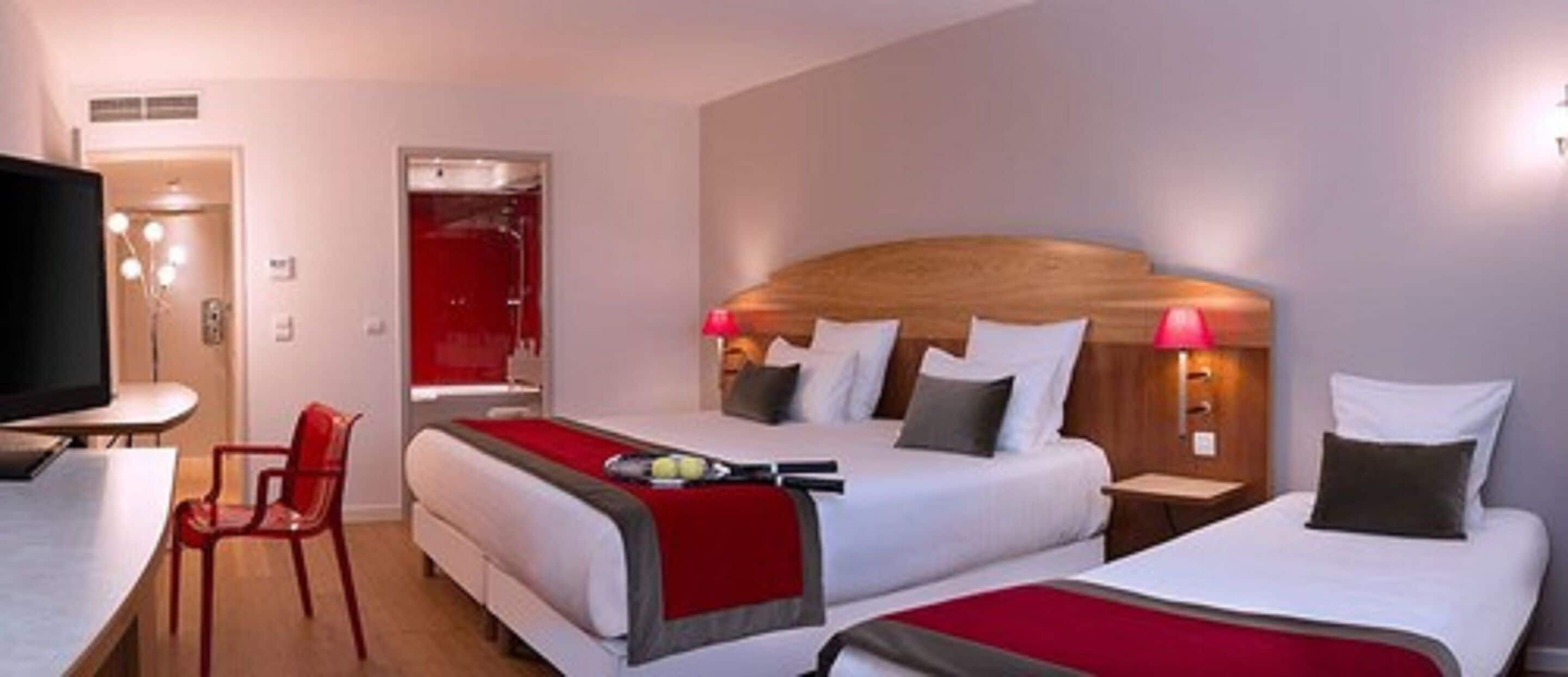 A hotel room with two beds, a TV, a desk, and a chair.