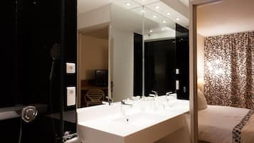 Un baño moderno con un espejo grande, un lavabo blanco y zona de ducha.