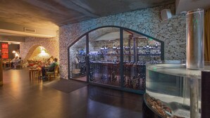 An interior with stone walls, a glass enclosure with wine bottles, and a fish tank. - C Suites (Nîmes)