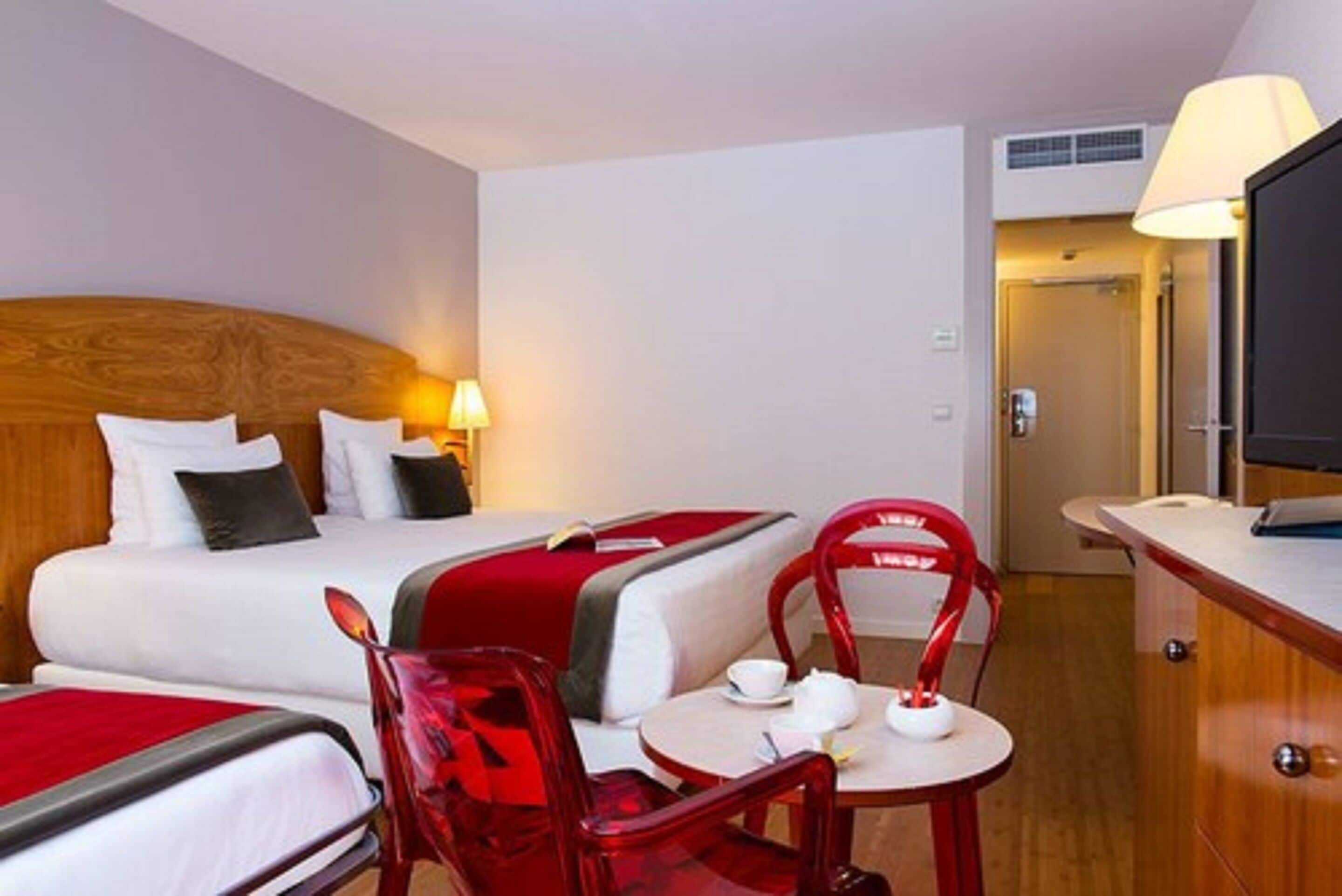 Habitación de hotel con dos camas, un escritorio, una silla y una mesa con una taza y un platillo.