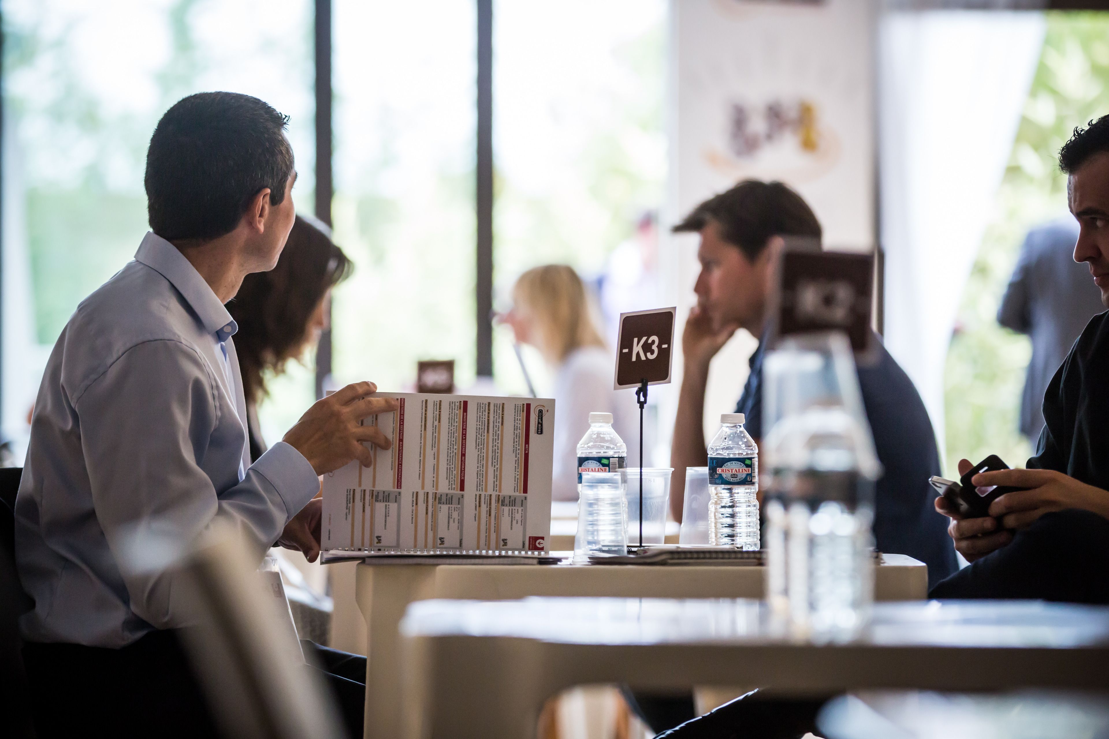 Une salle de conférence équipée de tables, de chaises et accueillant des participants.