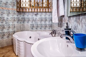 Une salle de bain avec une baignoire blanche, un lavabo et une tasse bleue.