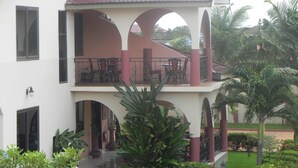 A two-story building with a balcony, potted plants, and a tiled roof.